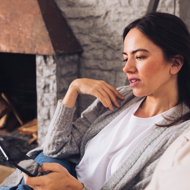 Modern woman sitting on the sofa using a tablet