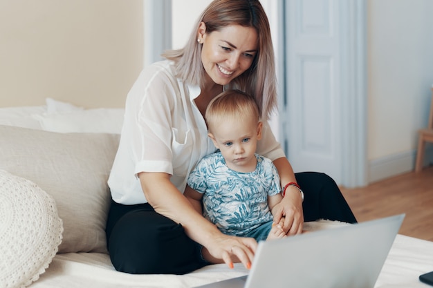 Modern woman working with child. Multi-tasking, freelance and motherhood concept