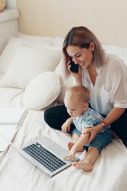 Modern woman working with child. Multi-tasking, freelance and motherhood concept