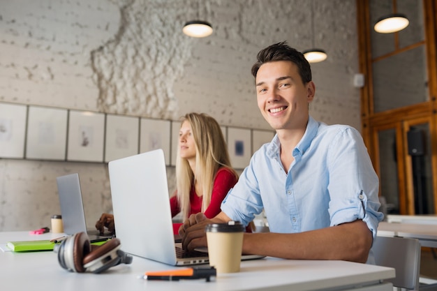 Modern young man and woman working on laptop in open space co-working office room,