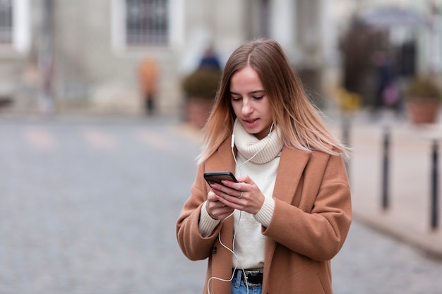 Modern young woman listening to music on earphones