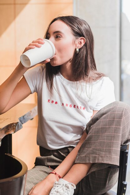 Modern young woman sitting in cafe drinking the coffee