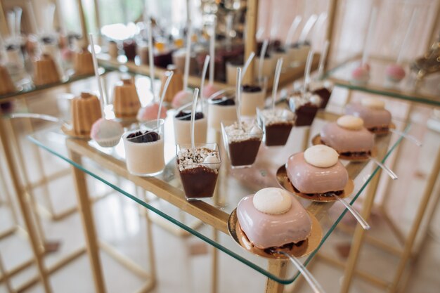 Molds with portion desserts and biscuit cookies covered pink cream are on the candy bar