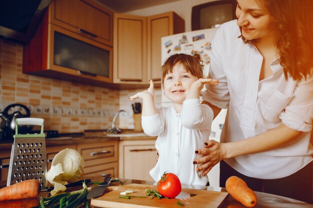 Mom along with her daughter cooks vegetables at home in the kitchen