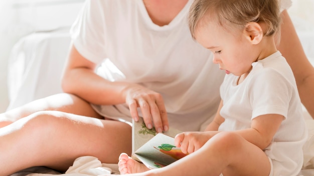 Mom and baby sitting in bed with book