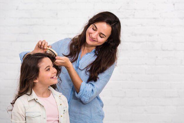 Mom brushing her daughters hair