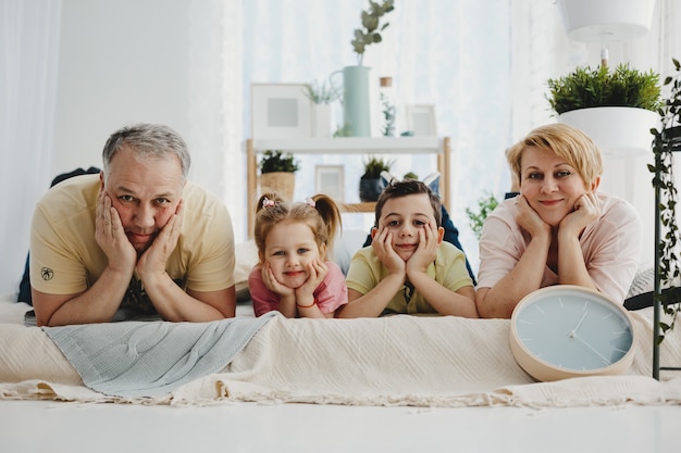 Mom and dad lie with their children in the same poses on the bed