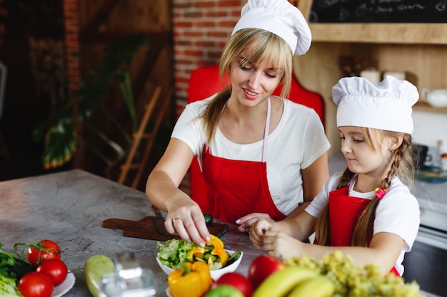 Free Photo mom and daughter have fun on the kitchen cooking different vegetables for a dinner