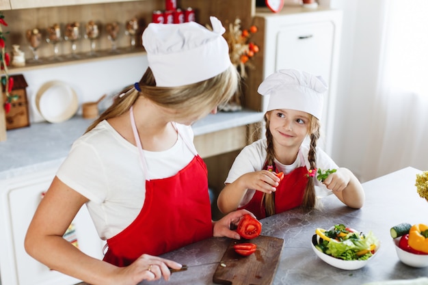 Mom and daughter have fun on the kitchen cooking different vegetables for a dinner