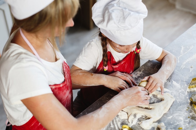 Free Photo mom and daughter have fun preparing cookies with milk at a dinner table in cosy kitchen