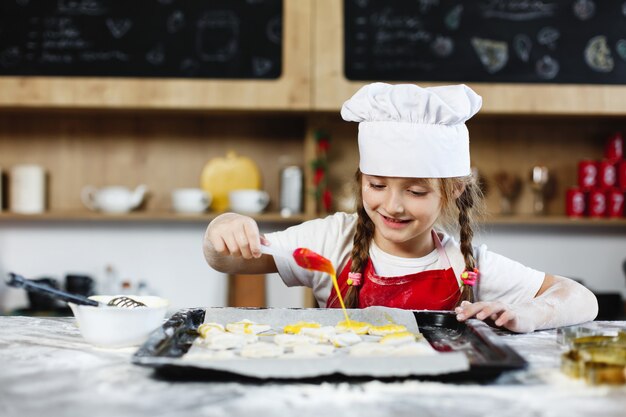  Mom and daughter have fun preparing cookies with milk at a dinner table in cosy kitchen