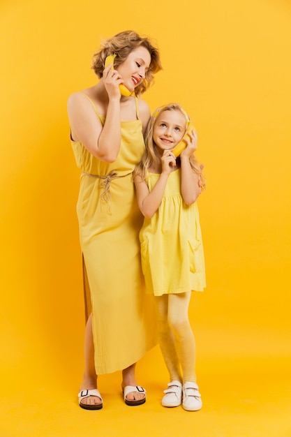 Free photo mom and daughter using bananas as phone