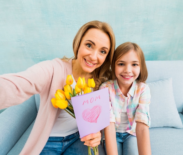 Free photo mom and daughter with present smiling taking photo