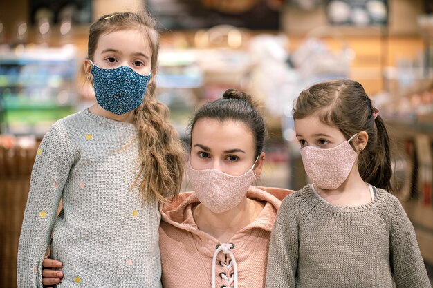 Mom and daughters shop in masks at the store during quarantine due to the coronavirus pandemic close up.