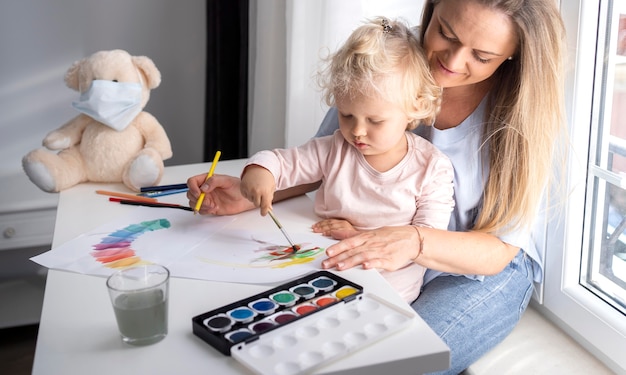 Mom helping child painting at home