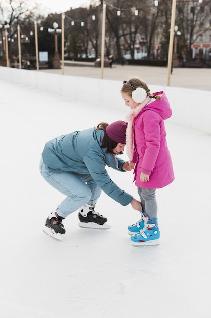 Mom helping cute daughter full shot