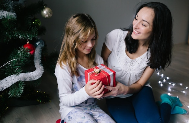 Mom and her cute daughter girl exchanging gifts.