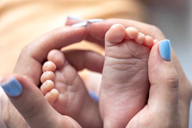 Mom holds the legs of a newborn baby in her hands