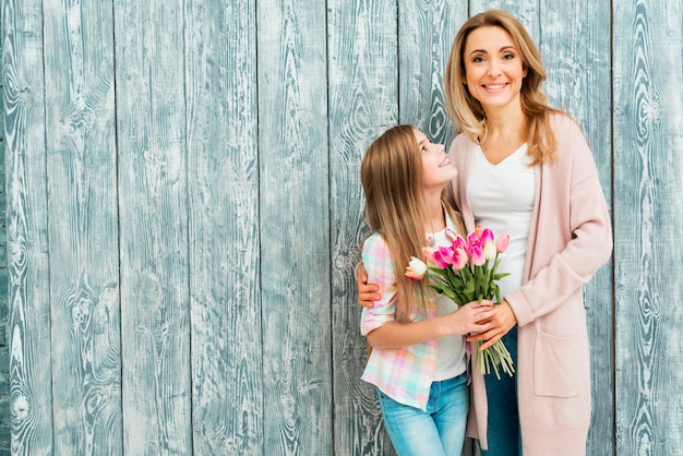 Free photo mom hugging daughter and smiling with flowers