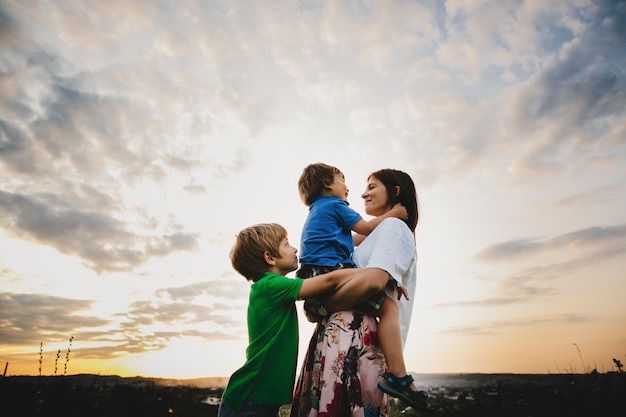 Mom hugs with her two little sons tender standing in the rays