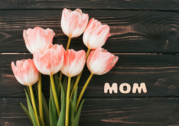 Mom inscription with tulips bouquet on wooden table