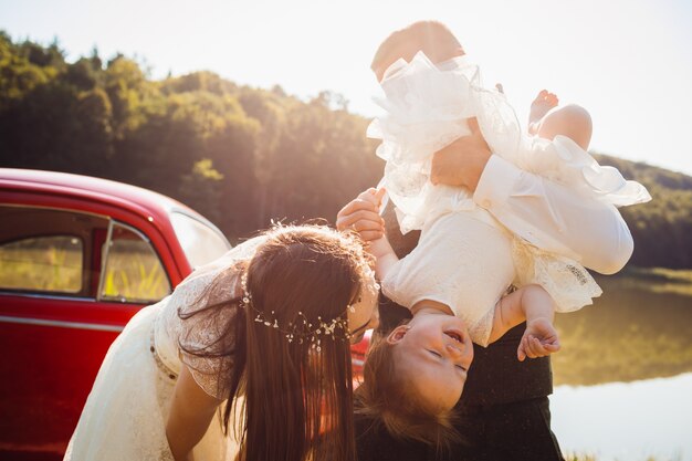 Mom plays with little daughter while dad holds her in his arms 