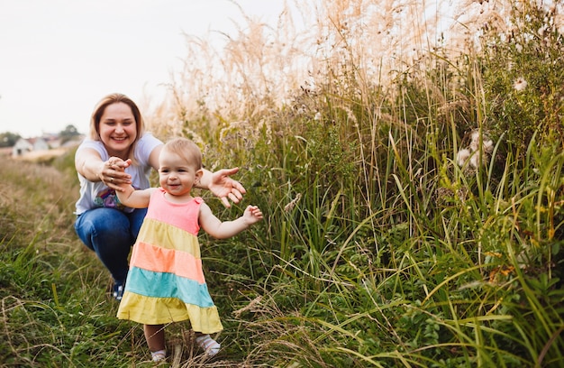 Mom plays with little girl in tall grass