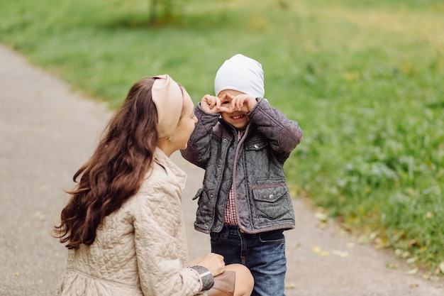 Free photo mom and son walking and having fun together in the autumn park.