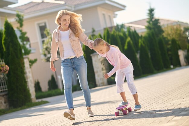 Mom supporting a girl while she skateboarding