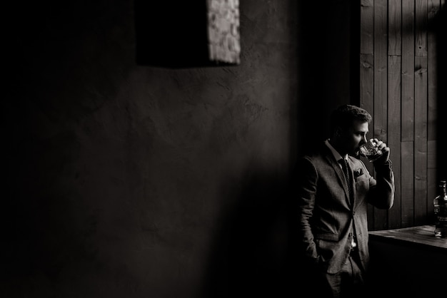 Monochrome view of handsom businessman in the room is drinking alcohol drink near the window