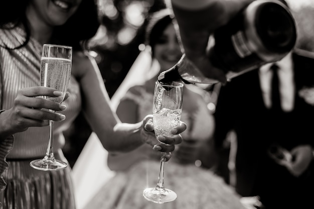 Free Photo monochrome view of a  pouring bottle into glasses and champagne glasses in tender women's hands