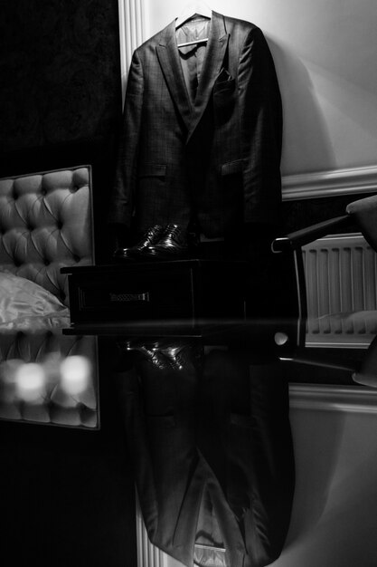 Monochrome view of the wedding attire for a groom reflecting on the glass table