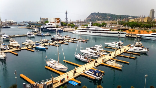 Moored yachts in the Mediterranean sea port, buildings, greenery in Barcelona, Spain