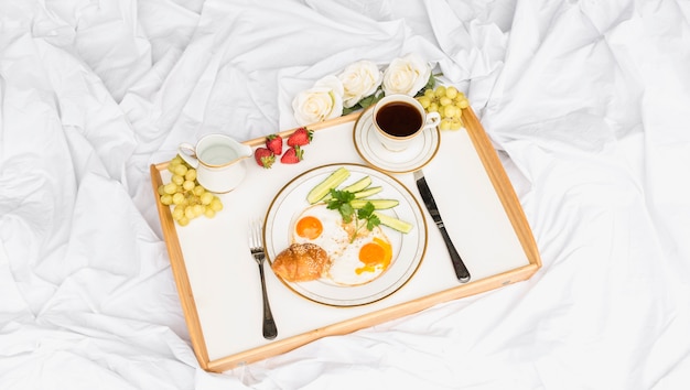 Morning breakfast tray on crumpled bed sheet