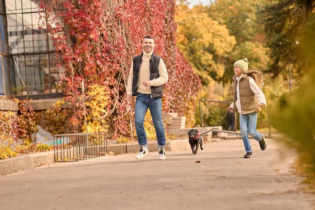 Free Photo morning walk. a man and a girl running with a dog