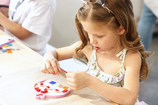 The mosaic puzzle art for kids, children's creative game. The hands are playing mosaic at table. Colorful multi-colored details close up. Creativity, children's development and learning concept