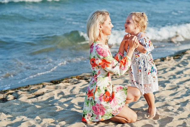 Mother and beautiful daughter having fun on the beach Portrait of happy woman with cute little girl on vacation