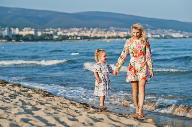 Mother and beautiful daughter having fun on the beach Portrait of happy woman with cute little girl on vacation