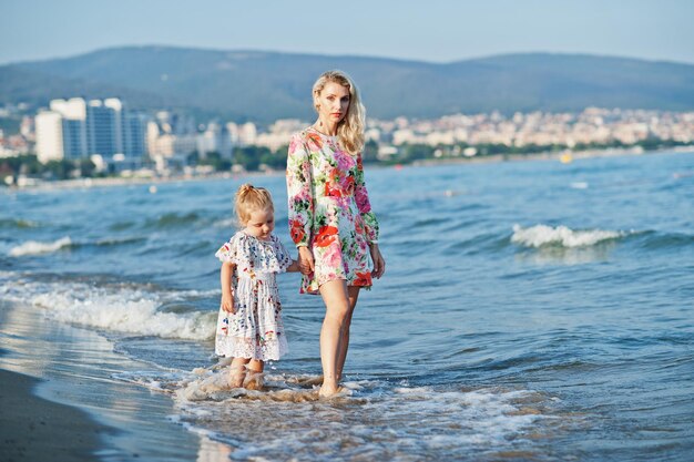 Mother and beautiful daughter having fun on the beach Portrait of happy woman with cute little girl on vacation