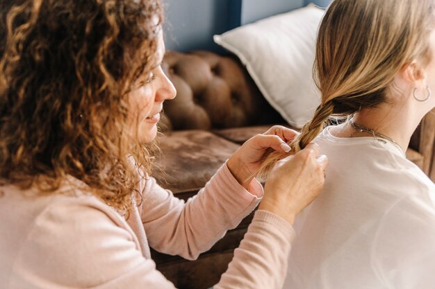 Free Photo mother braiding hair of unrecognizable daughter