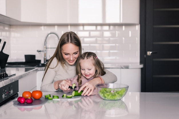 Mother and child daughter are preparing the vegetables salad