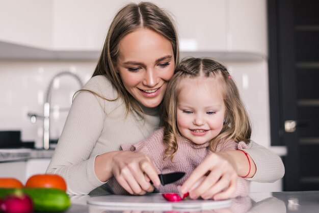 Mother and child daughter are preparing the vegetables salad