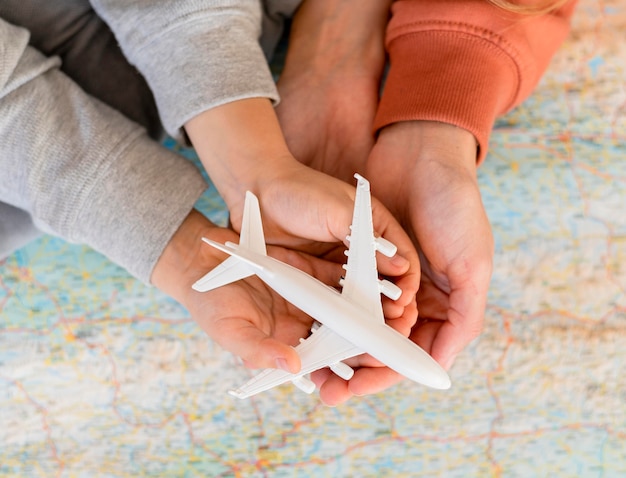 Free photo mother and child at home holding airplane figurine on top of map