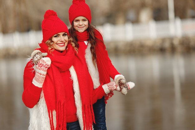 Mother and child in knitted winter hats on family Christmas vacation. Handmade wool hat and scarf for mom and kid. Knitting for kids. Knit outerwear. Woman and little girl in a park.