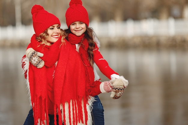 Mother and child in knitted winter hats on family Christmas vacation. Handmade wool hat and scarf for mom and kid. Knitting for kids. Knit outerwear. Woman and little girl in a park.