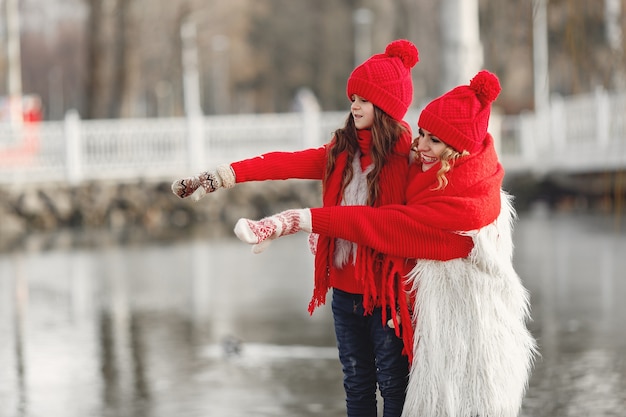 Mother and child in knitted winter hats on family Christmas vacation. Handmade wool hat and scarf for mom and kid. Knitting for kids. Knit outerwear. Woman and little girl in a park.