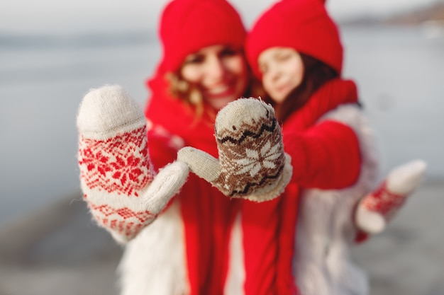 Free photo mother and child in knitted winter hats on family christmas vacation. handmade wool hat and scarf for mom and kid. knitting for kids. knit outerwear. woman and little girl in a park.