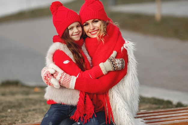 Free Photo mother and child in knitted winter hats on family christmas vacation. handmade wool hat and scarf for mom and kid. knitting for kids. knit outerwear. woman and little girl in a park.