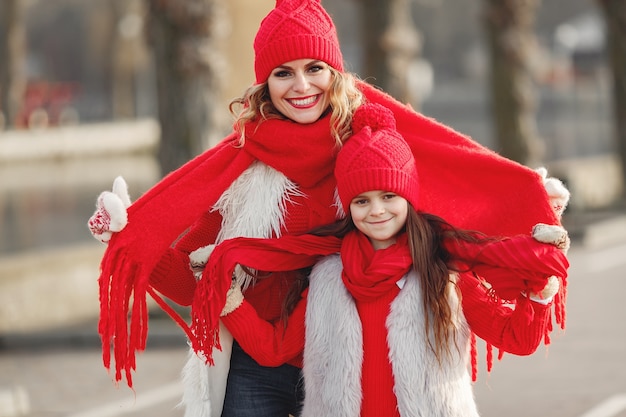 Mother and child in knitted winter hats on family Christmas vacation. Handmade wool hat and scarf for mom and kid. Knitting for kids. Knit outerwear. Woman and little girl in a park.