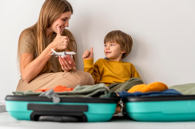 Mother and child with luggage at home giving thumbs up